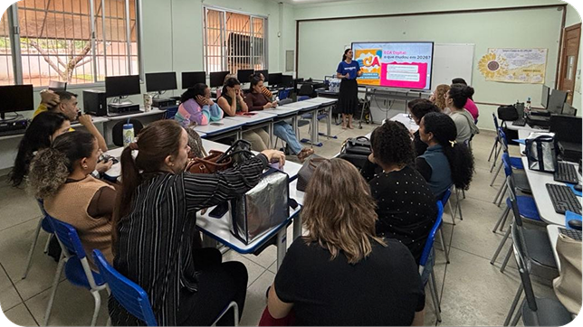 Formadora apresenta um slide sobre ECA Digital na tela interativa para professoras em um laboratório de informática