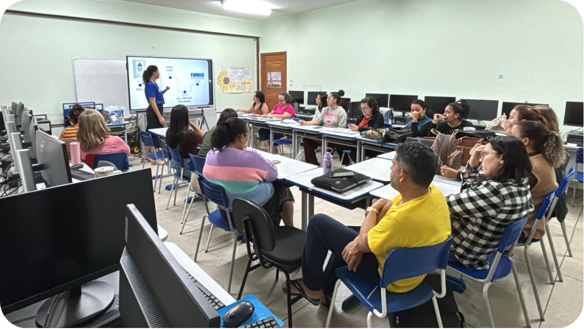 Formadora explica uma linha do tempo com PNED e FUNDEB na tela interativa para professores em um laboratório de informática